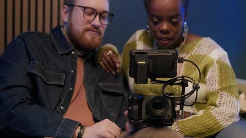 Two People Inspecting a Camera Setup Indoors