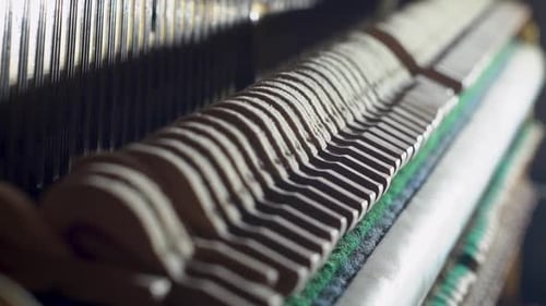 A slow-motion close-up shot of the inside of an old upright piano, showing the hammers and felts str