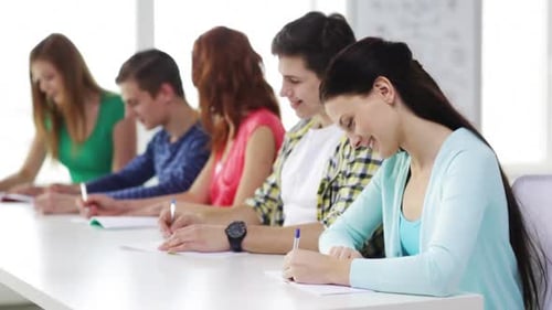 Smiling students work together taking notes in a school classroom