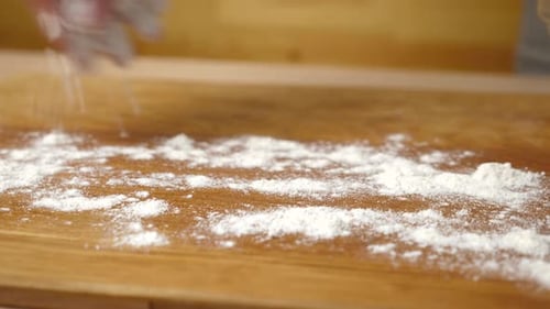 Flour Being Spread on a Wooden Cutting Board