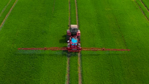 Aerial View of Crop Sprayer Spraying Pesticide on Wheat Field in Rural Farmland Farming Tractor
