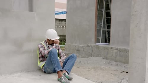 Indian man manager supervisor worker engineer employee sits leaning against the wall of a housing pr