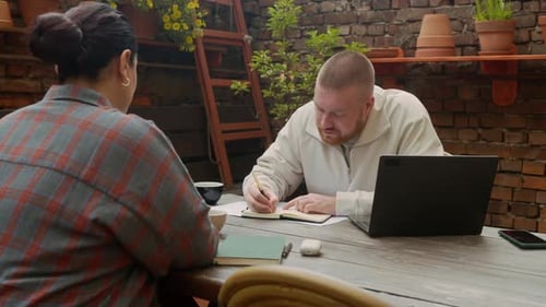Two adults working collaboratively at an outdoor table