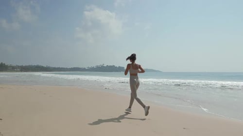 Cinematic Aerial Shot of Female Beach Runner During Outdoor Workout