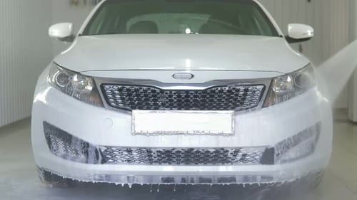 Worker in Garage Automobile Service is Washing a Car in the Suds By Noncontact High Pressure Water
