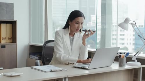 Businesswoman Talking on Speaker Phone at Work in Office