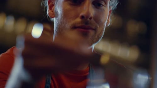 Closeup Attractive Bartender Putting Ice Cube Into Glass Indoors. Confident Bar Man Is Using Spec...