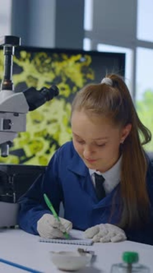 Focused Teen Girl Using Microscope in Laboratory Setting