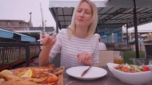 Lunch in restaurant, woman eating grilled dorado fish with grilled asparagus