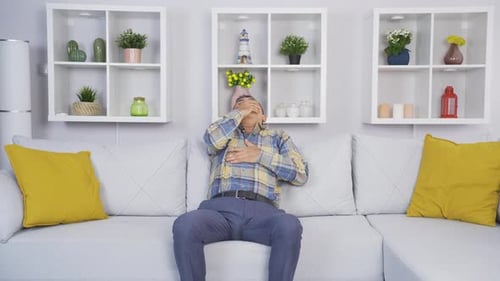 Man Coughing While Sitting on Couch Indoors