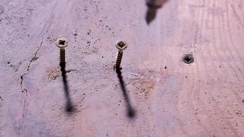 Screwing two bolts in a board. DIY. Craftsman at work.