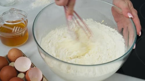 Stirring a dough of flour and eggs in a pastry making bowl.