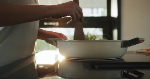 Woman Stirring Food in a Pan with a Spoon