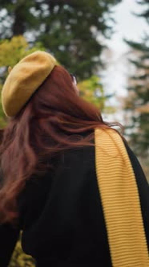 Belle dame aux cheveux rouges bouclés tournant joyeusement dans un jardin animé