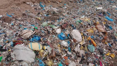 Aerial circle over a large pile of plastic garbage in a landfill.