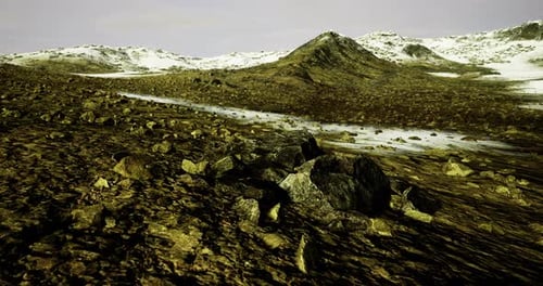 Vast Rocky Terrain Under a Pale Sky with Distant Snow Capped Peaks