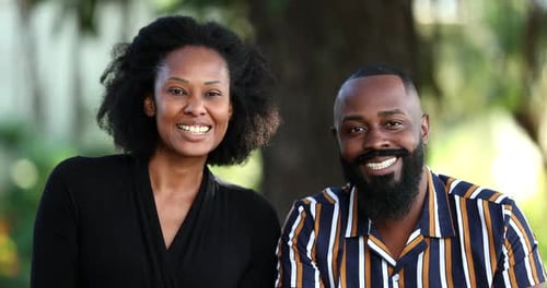 Two African couple smiling at camera outside at park