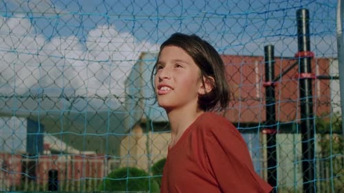 Child Hitting Soccer Ball with Head in Urban Setting