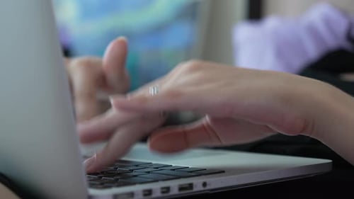 Pessoa digitando no teclado de um laptop cinza. Close-up