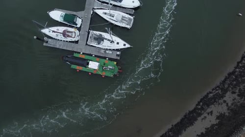 Top down aerial drone view following wake trail above luxury moored private marina sailing ships and