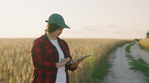 Portrait of a Female Farmer in a Cap Who Works in the Field with a Tablet