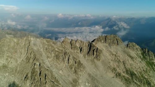 Aerial view over the alpine mountain chain. High view of the alps mountain peaks. Picturesque clouds