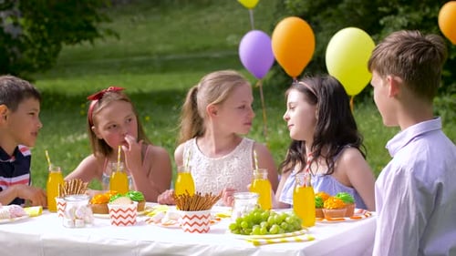Happy children celebrating a summer birthday party in the garden with friends