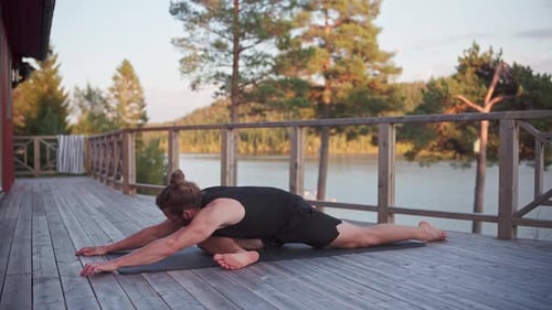 Caucasian Man Stretching On Yoga Mat With View Of The Lake In Norway. - close up