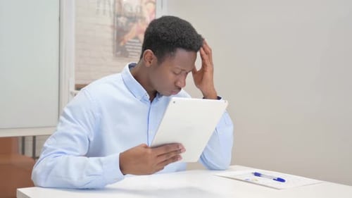 African Businessman with Loss on Tablet in Office