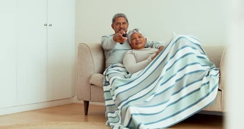 Senior Couple Relaxing on Sofa Under Blanket