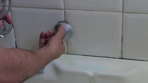 Steady shot of a man loosening a tap to be repaired