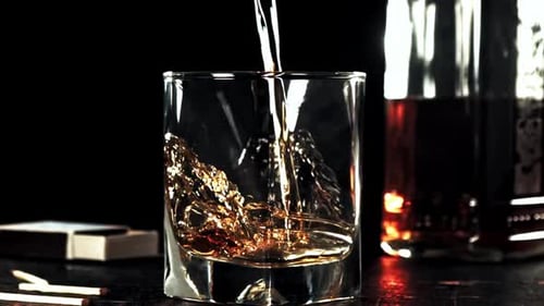Super Slow Motion Whiskey with Splashes Flows Into a Glass of Ice