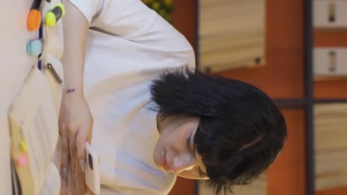 Young Woman Types on Phone at Desk