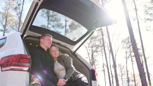 Affectionate couple relaxing in car trunk enjoying nature