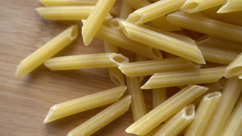 Penne Pasta Piled on Wooden Surface Close Up