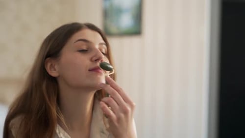 Woman Massaging Face with Jade Roller at Home