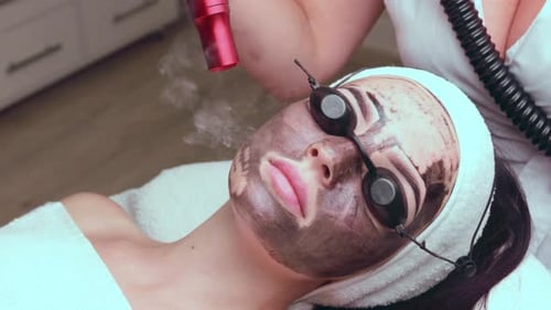 Woman Receiving Laser Facial Treatment at Home