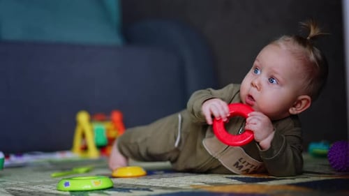 Blond Infant Playing with Toys on a Rug