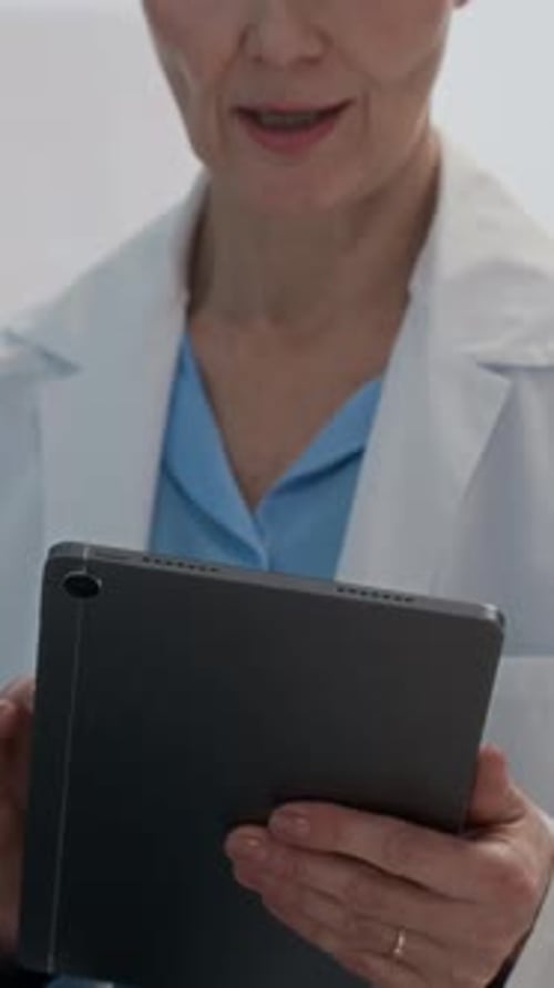 Female Practitioner with Tablet Supporting Sick Patient in Ward