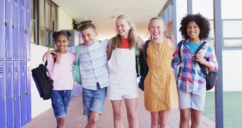 Portrait of happy diverse schoolchildren at locker in school
