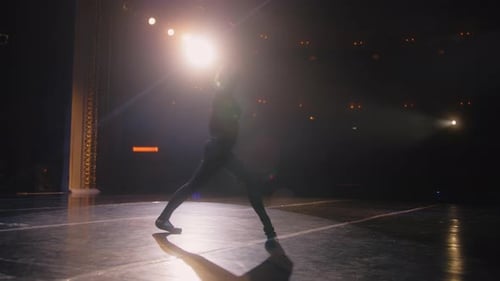 Ballerina Practices Ballet Movements on Theater Stage