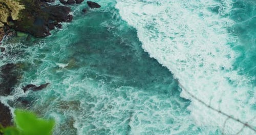 Top Down Static View From Above of Giant Ocean Waves Crashing and Foaming on Empty Rocky Tropical