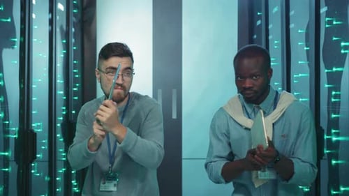 Men in Server Room with Tablets Make Shooting Gestures