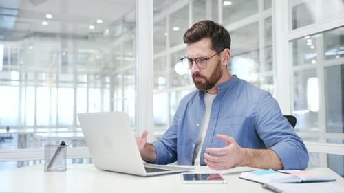 Frustrated Man Looking at Laptop in Office