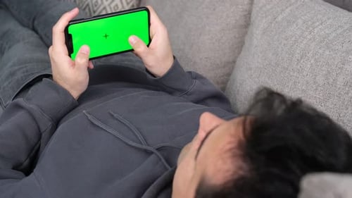 Mann hält Greenscreen-Handy