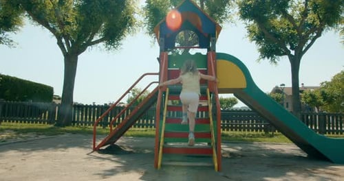 Child Girl Run and Slide on Playground at Summertime