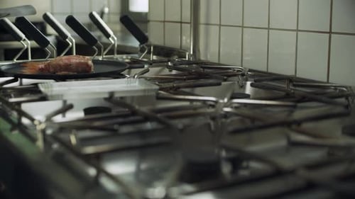 Professional Restaurant Chef Cooking Fish Wrapped in Mortadella on a Skillet Over