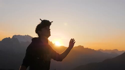 A man wearing DJI fpv drone racing goggles looking up in the sky during sunrise as he flies and film