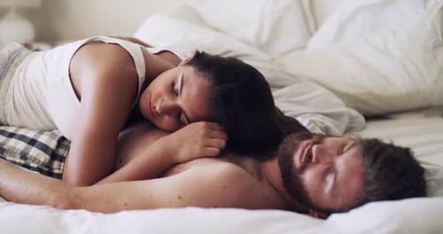 Ein glückliches junges Paar, das zu Hause zusammen ein Nickerchen im Bett macht