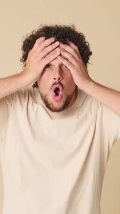 Shocked man looking at the camera with big eyes, says wow, isolated on beige background in studio
